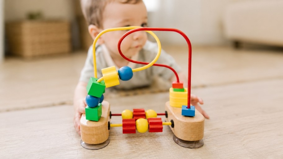 a baby with a wooden bead maze toy