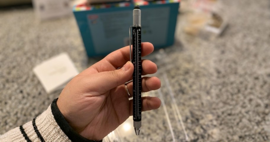 a hand holding a black multitool pen