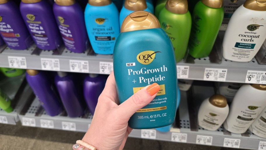 hand holding a bottle of hair care in front of a store shelf