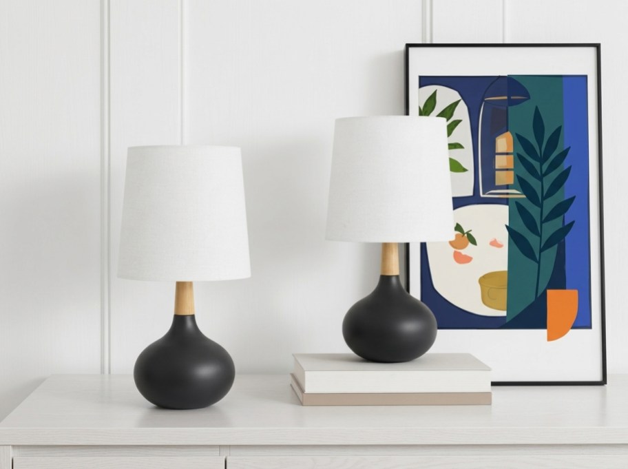 2 lamps on a table with art
