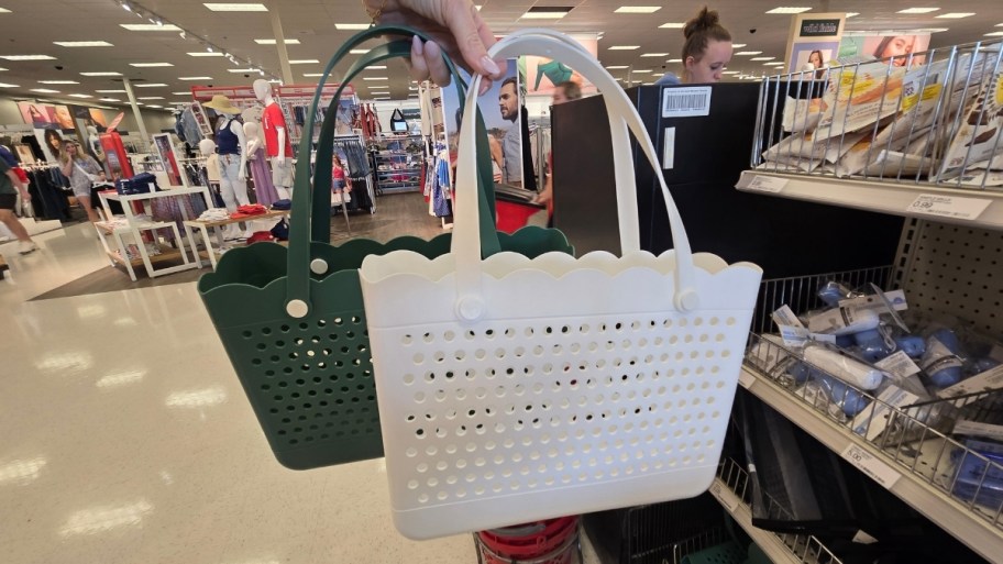 a womans hand holding two bullseye jelly totes in green and white