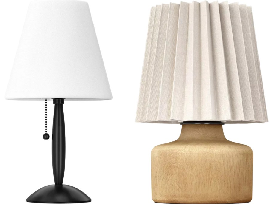 Two table lamps are side by side. The left lamp has a sleek black base and a white shade with a pull chain. The right lamp features a wooden base and a pleated white shade.