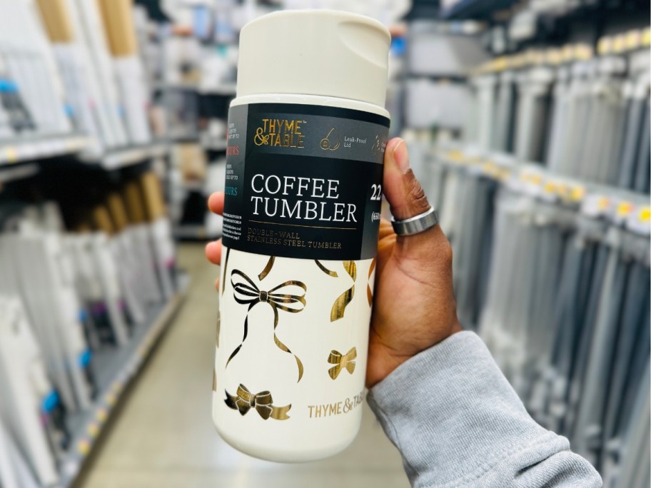 hand holding a coffee tumbler in cream with gold bows 