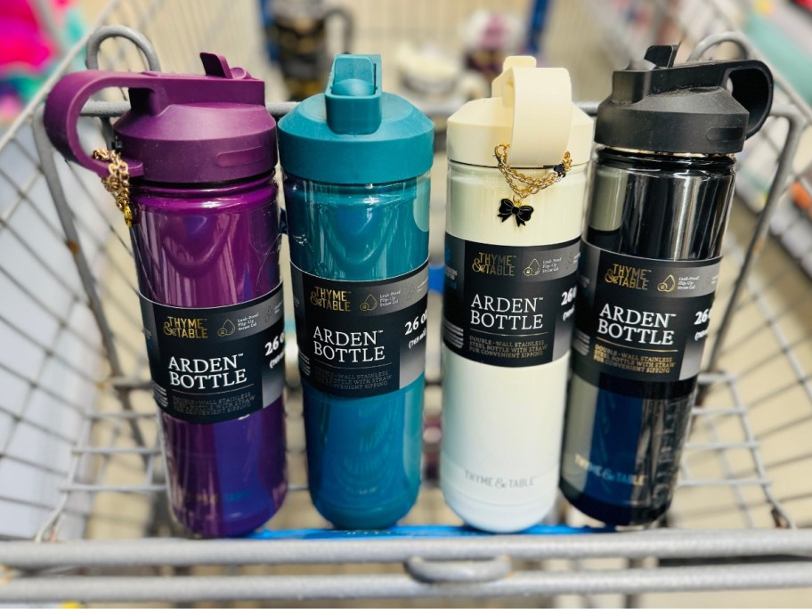 four different colors of Thyme & Table water bottles in a Walmart cart