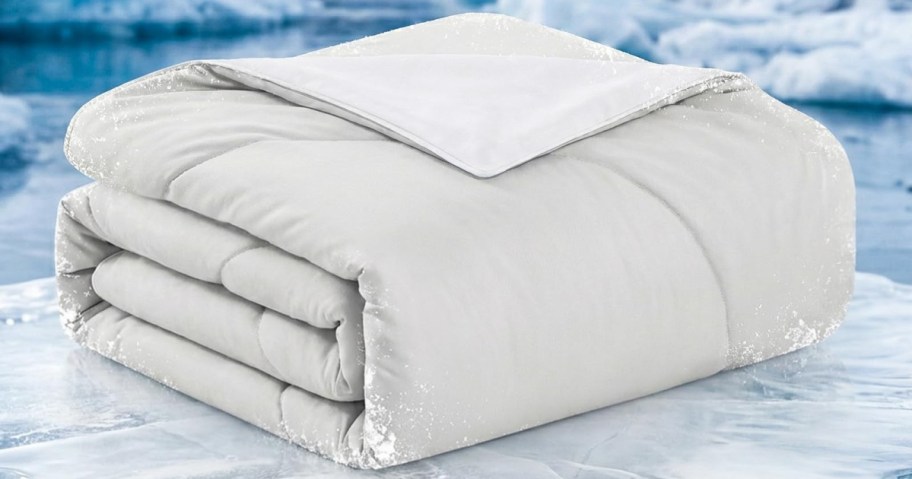 Folded white blanket on an icy surface, surrounded by a snowy backdrop.
