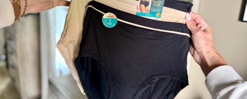 Hands hold three-pack of women's underwear, with black and beige pairs. A label reads "Vanity Fair" and "New 3 Pack."
