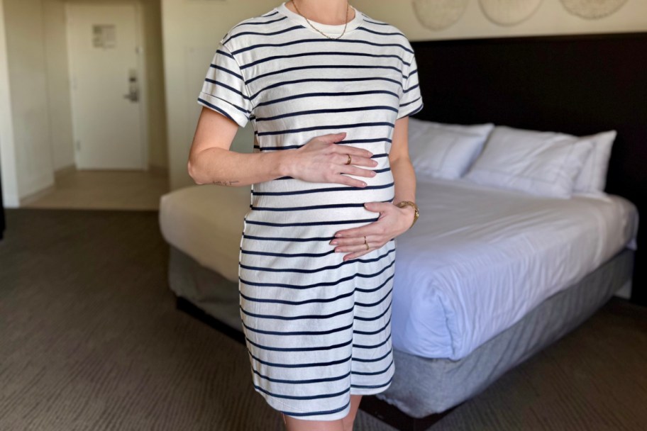 woman holding baby bump in black and white striped dress