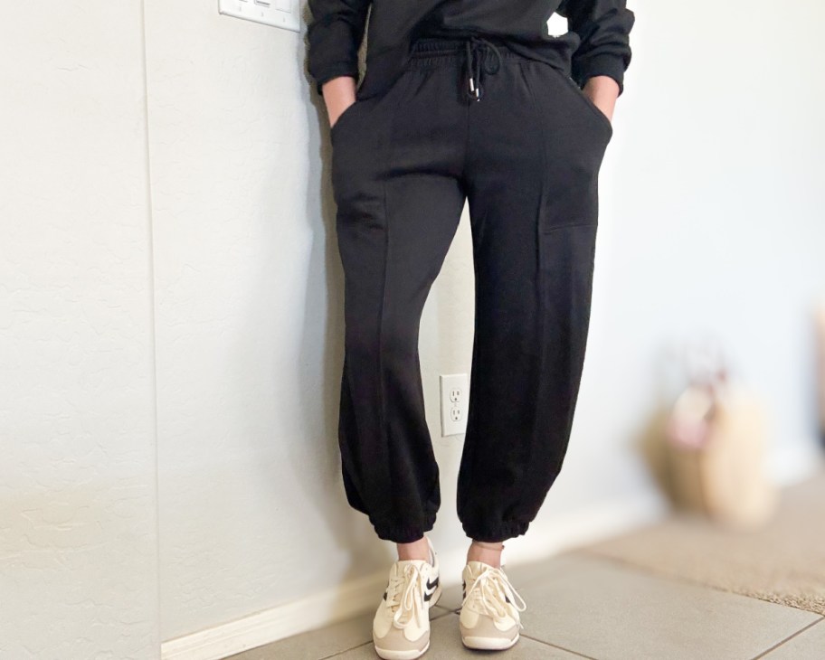 woman standing in black barrel leg pants