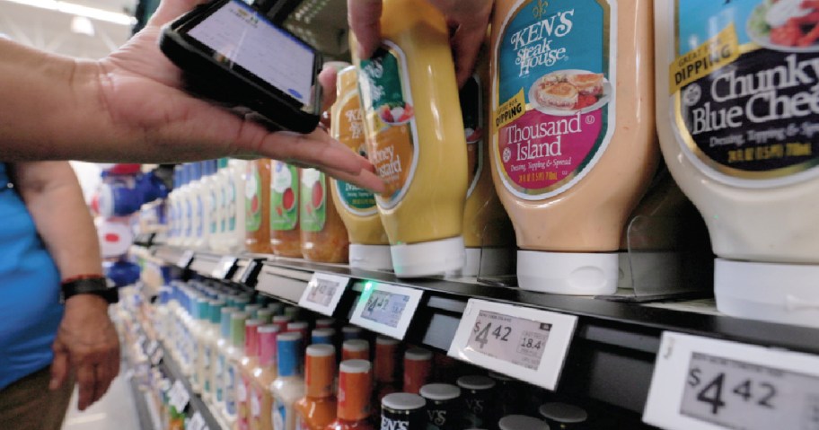 Woman holding a phone near salad dressing in a Walmart store