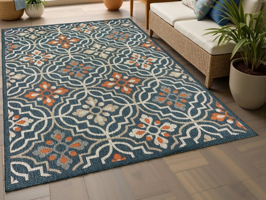 a green, tan, and orange medallion print rug in a sunroom