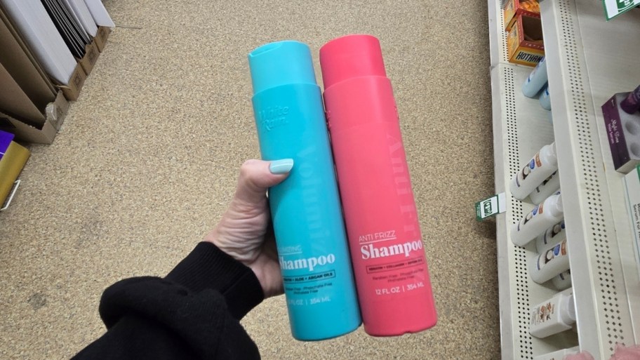 womans hand holding 2 bottle of white rain shampoo