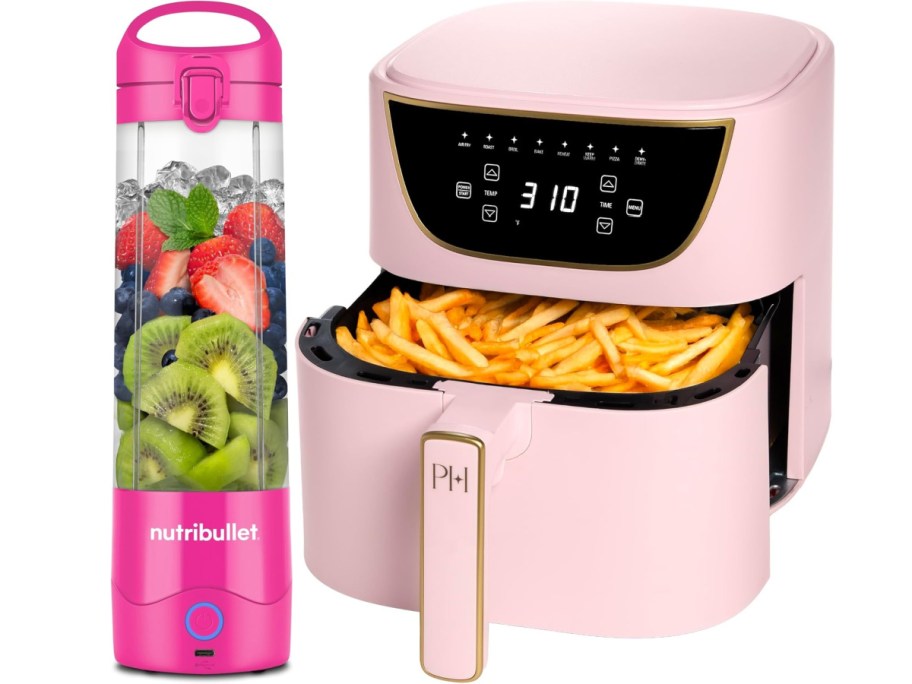 Pink air fryer filled with French fries and a matching pink portable blender with sliced fruit inside.