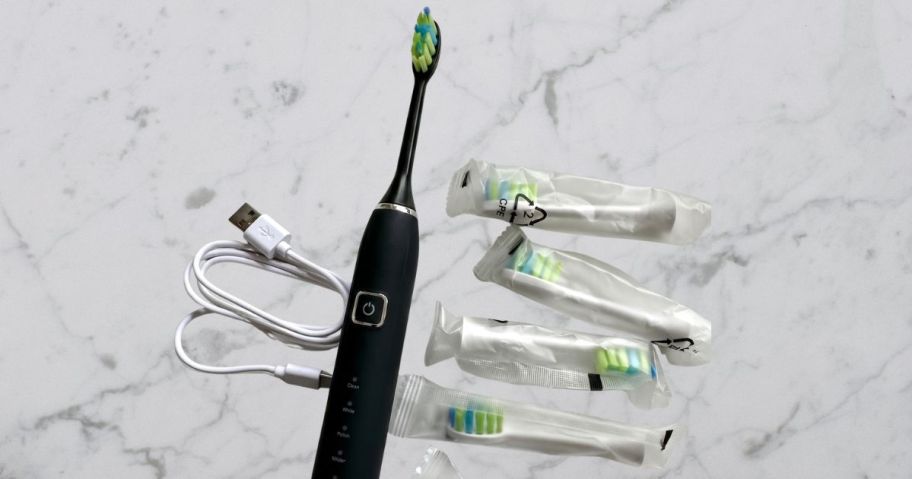7AM2M Travel Electric Toothbrush in Black w/ 6 Brush Heads on bathroom counter