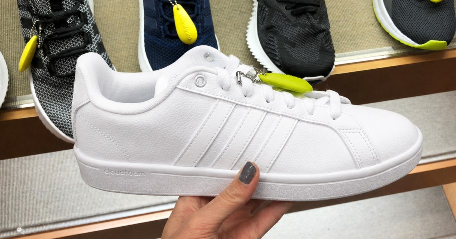 hand holding an all white adidas sneaker in store