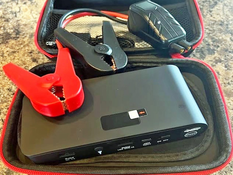 car battery jump starter with cables on top of its storage case