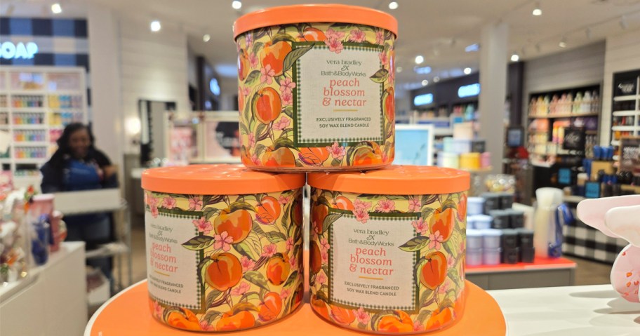stack of orange Bath & Body Works 3-Wick Candles in store