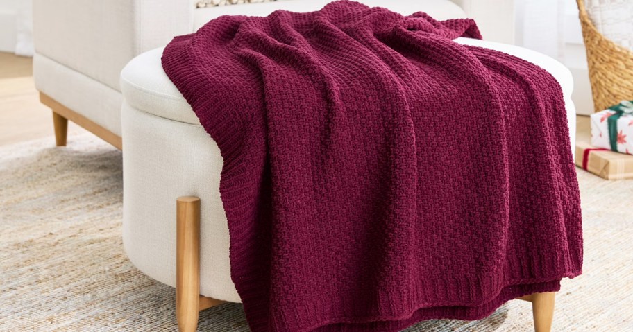 maroon knit throw blanket draped over an ottoman