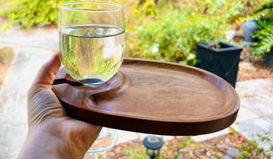 person holding a better homes & gardens tapas serving platter by a wine glass outside