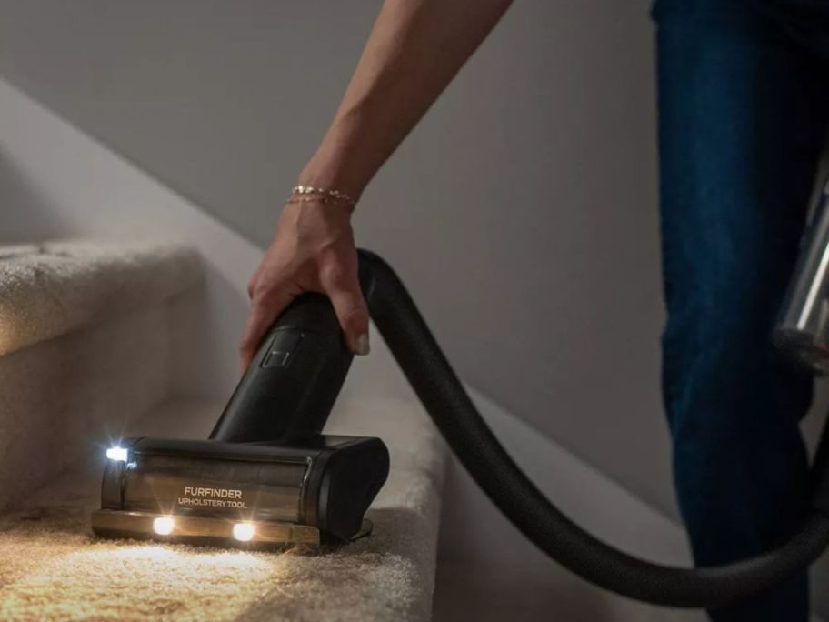 person using Bissell PowerClean DualBrush Cordless Stick Vacuum on stairs