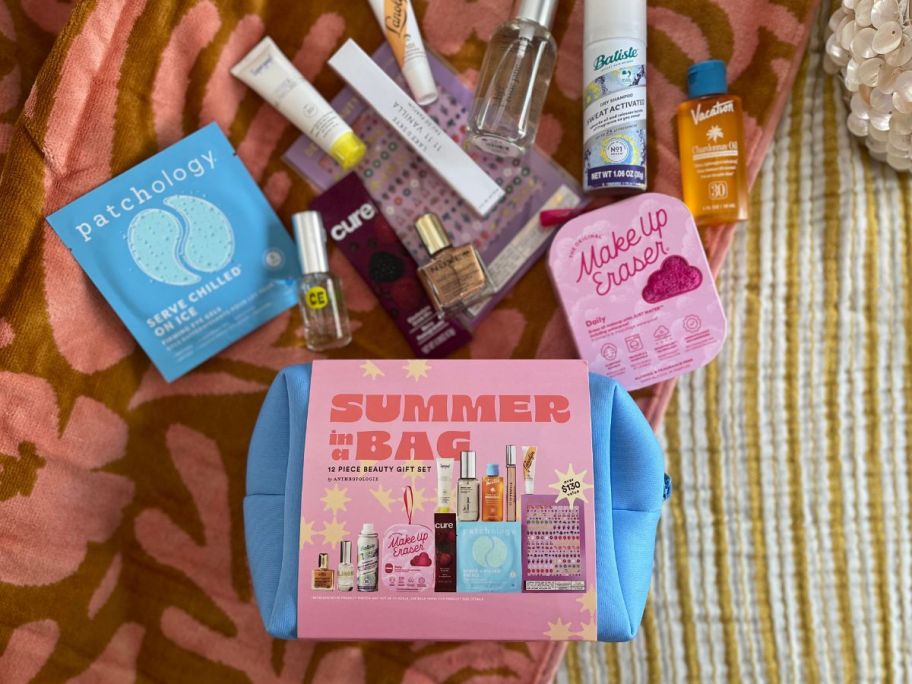 By Anthropologie 12-Piece Summer Beauty Bag and its contents laid out on blanket