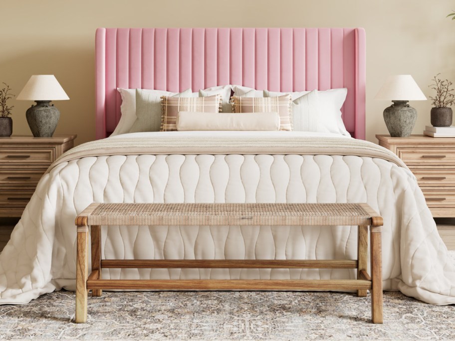Elegant bedroom with a pink velvet headboard and cream bedding. Wooden bench at the foot of the bed.