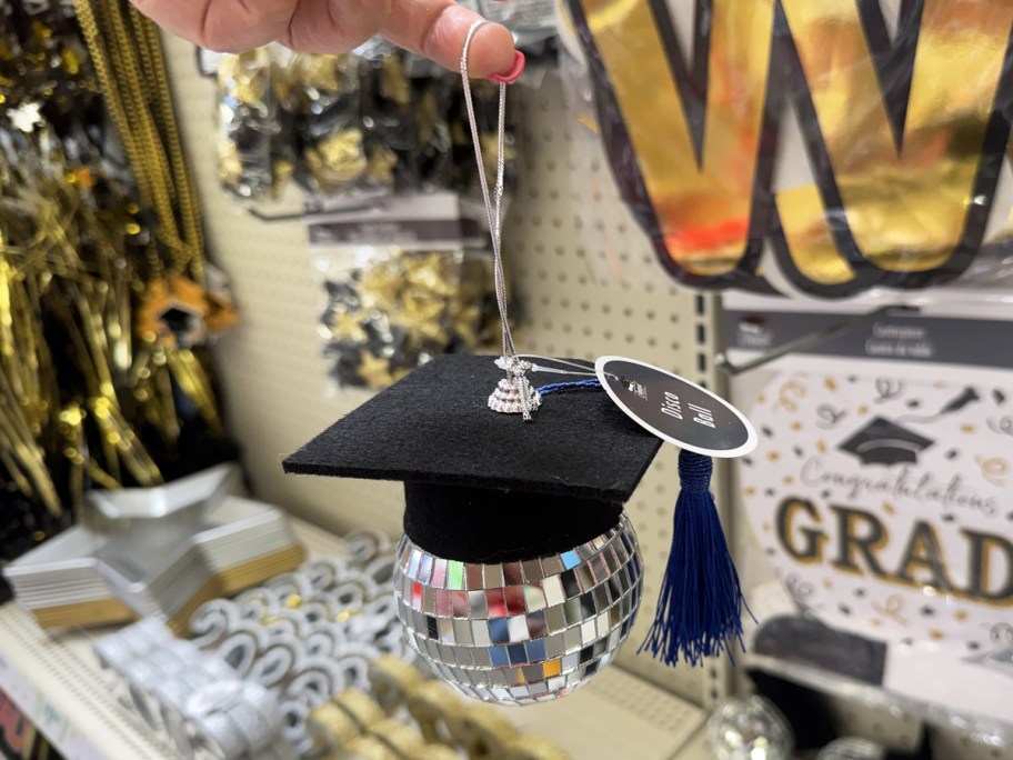 hand holding a disco ball ornament with a graduation cap