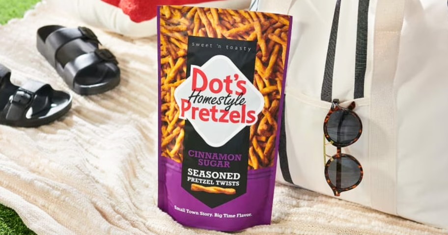 bag of Dot's Pretzels on a picnic blanket near bag and sandals