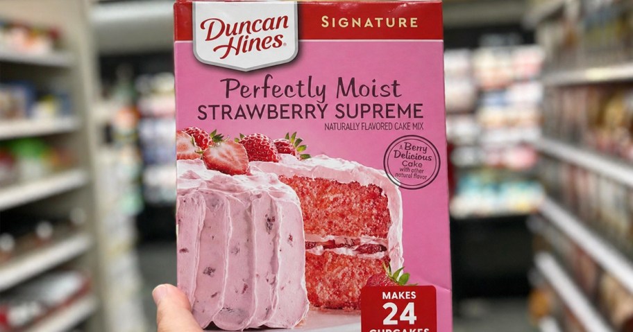 hand holding up a box of Duncan Hines Strawberry Supreme Cake Mix in store