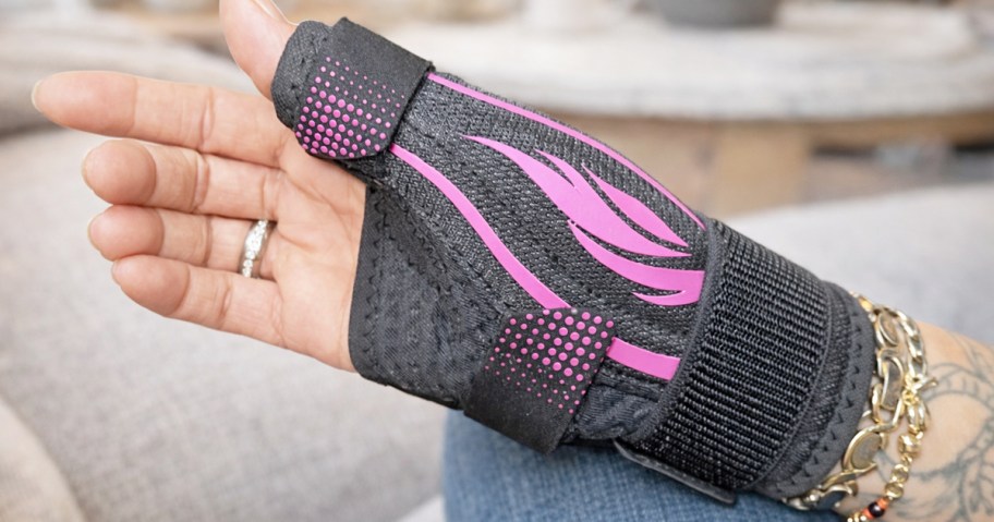 woman's hand wearing a black and pink wrist brace