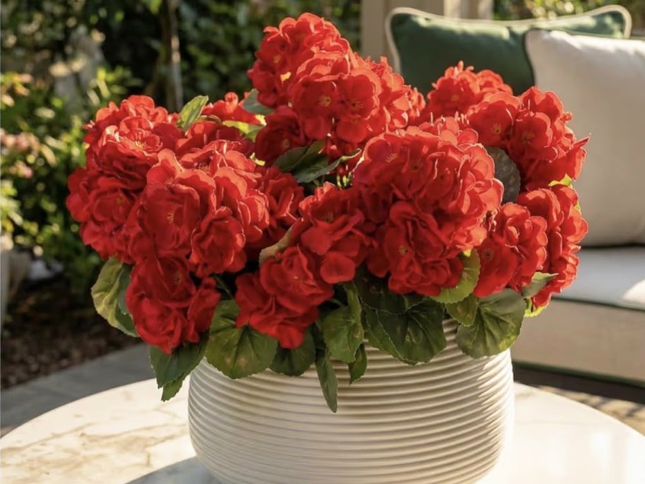 red artificial flowers in a white pot