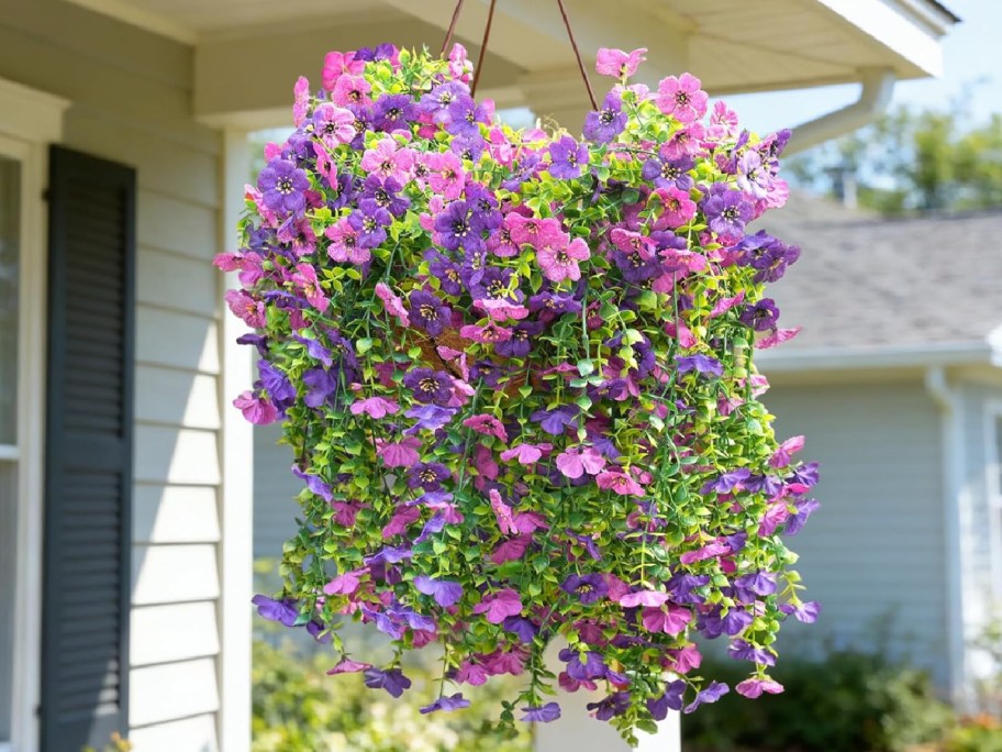 pink and purple faux flowers hanging outside in basket