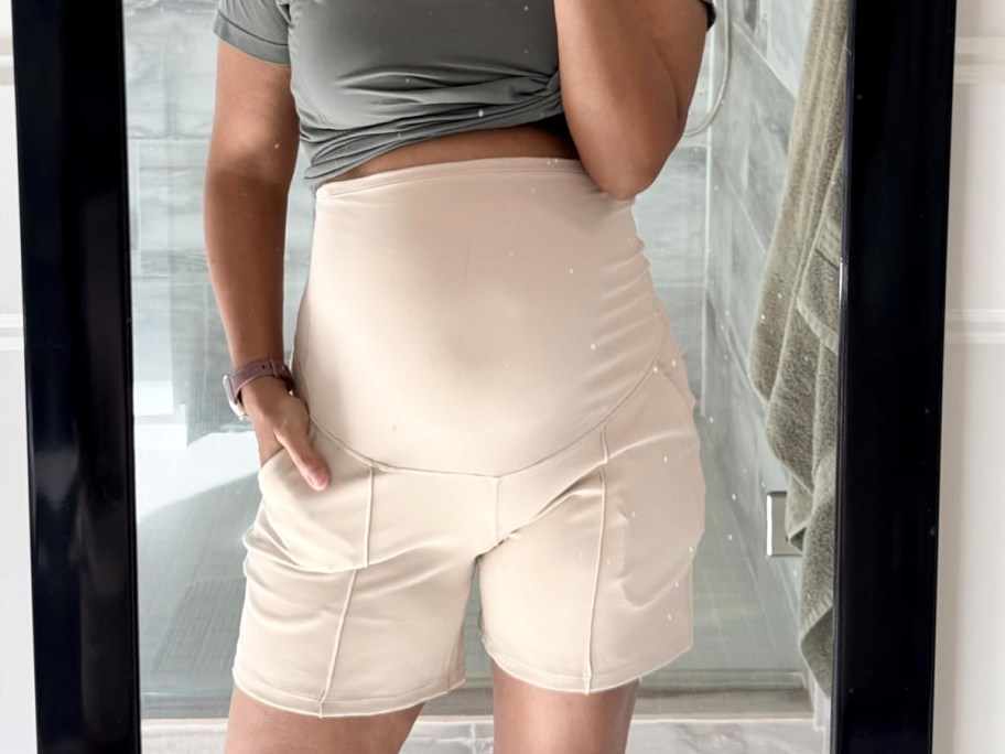 woman wearing green top and white maternity shorts