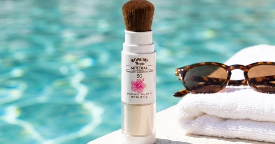 Hawaiian Tropic Mineral Powder Sunscreen Brush near towels, sunglasses, and pool