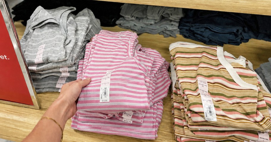 hand grabbing a striped tank top from a store display table