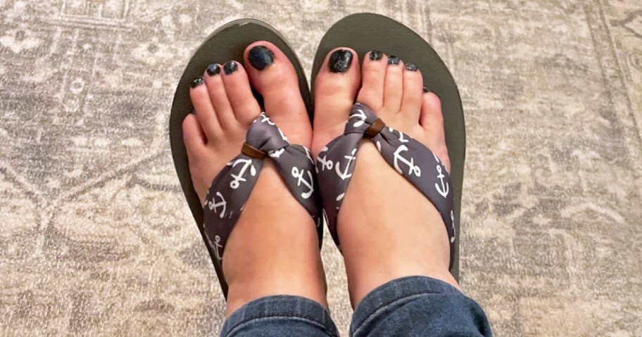 women's feet wearing anchor print flip flops