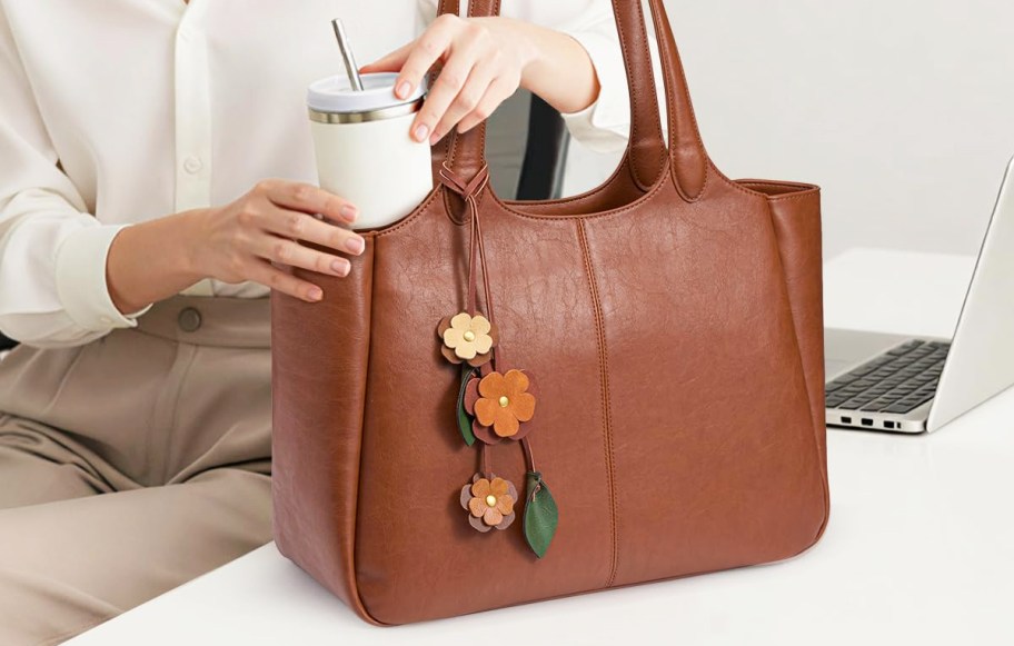 woman taking tumbler out from brown tote bag