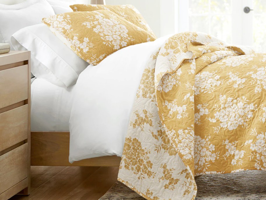 yellow and white quilt and shams set on a bed