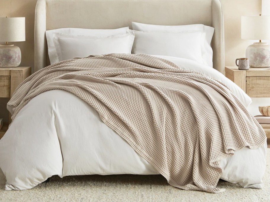 bed made with white comforter, sheets, and tan throw blanket