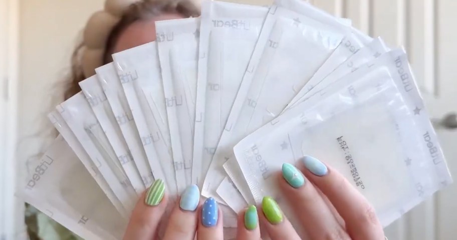 hands holding up multiple sheets of pimple patches