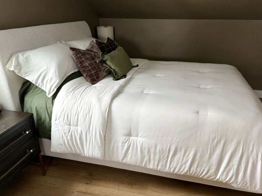 A bed with a white Litanika comforter set on it