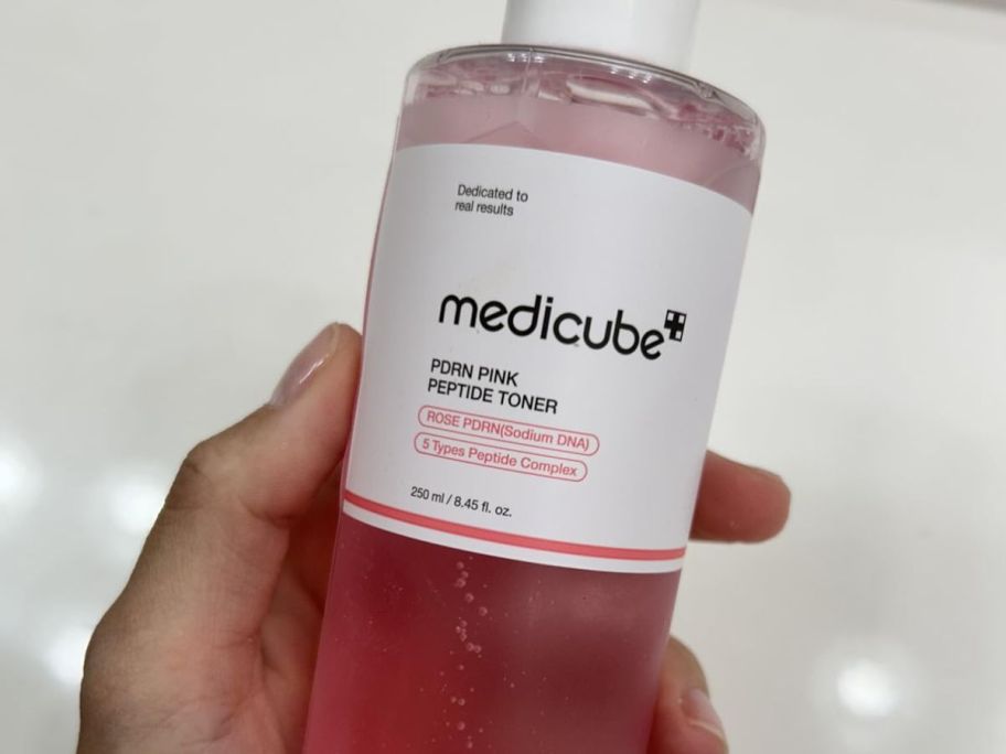 hand holding Medicube toner salmon