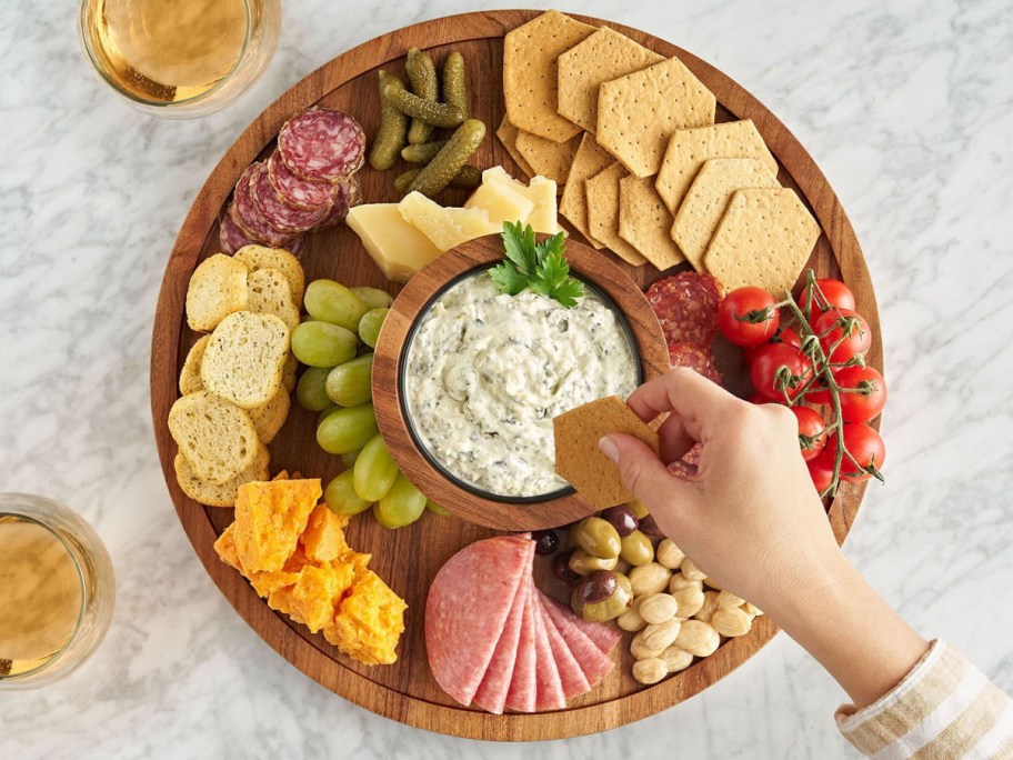 hand dipping a cracker in dip above a serving tray