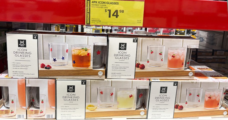 boxes of drinking glasses stacked in store with yellow sale sign above them