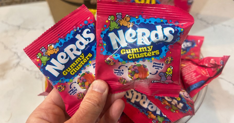 hand holding up two pink individual packs of nerds gummy clusters