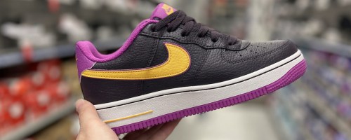hand holding up a black, purple, and yellow nike shoe in store