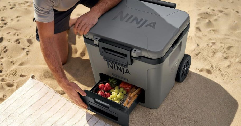 man opening Ninja FrostVault 30-qt Wheeled Cooler w/ Dry Zone at beach