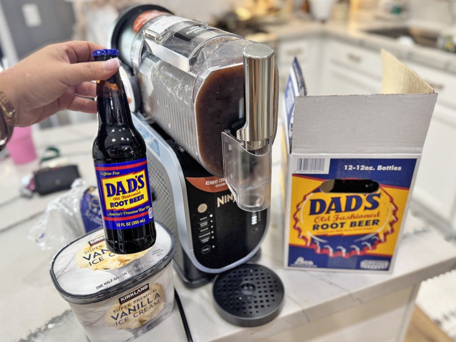 holding a bottle of Dad's Root Beer next to Ninja SLUSHi machine