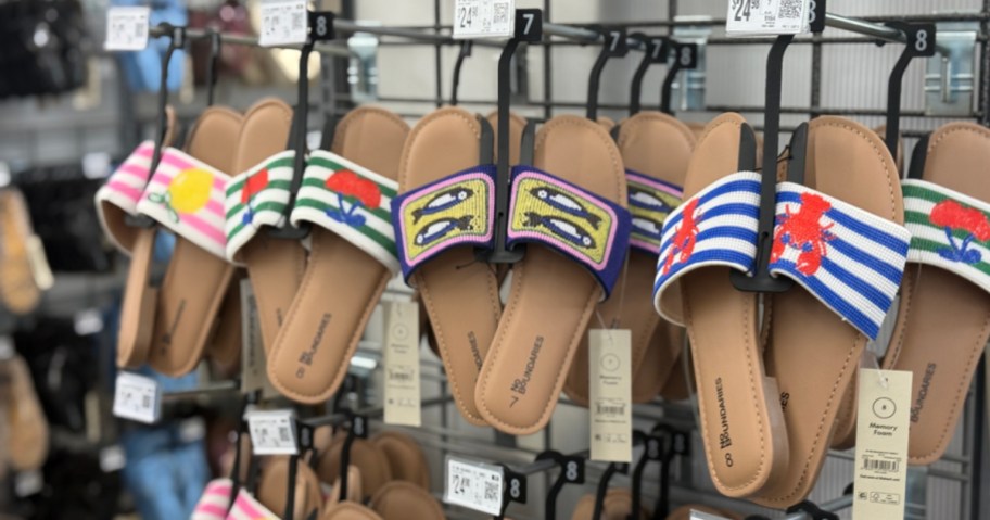 Colorful women's sandals with beaded straps, featuring floral and nautical designs, hang on a store display.