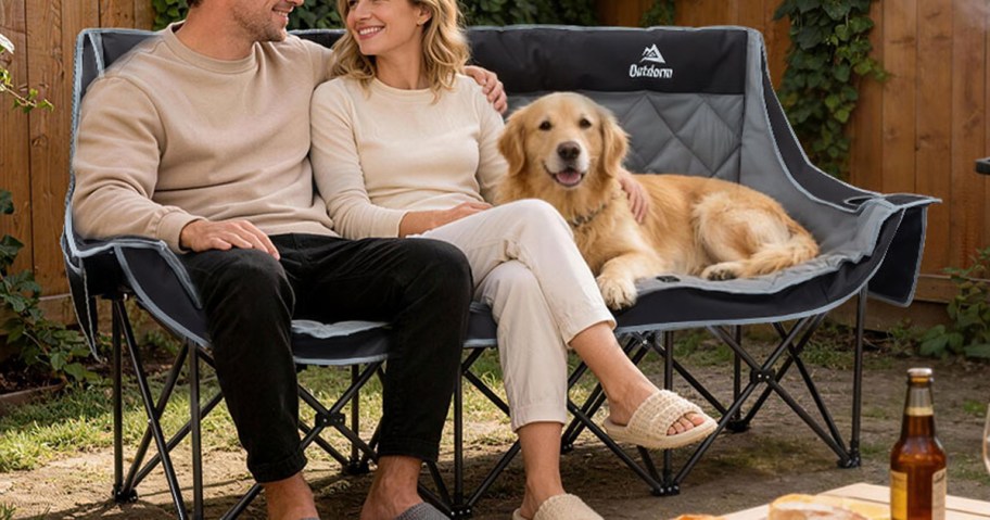 man, woman, and dog sitting on 3-person camping chair