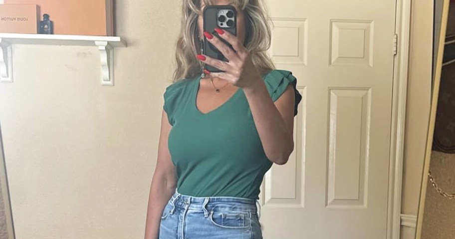 woman taking photo wearing green top and jeans